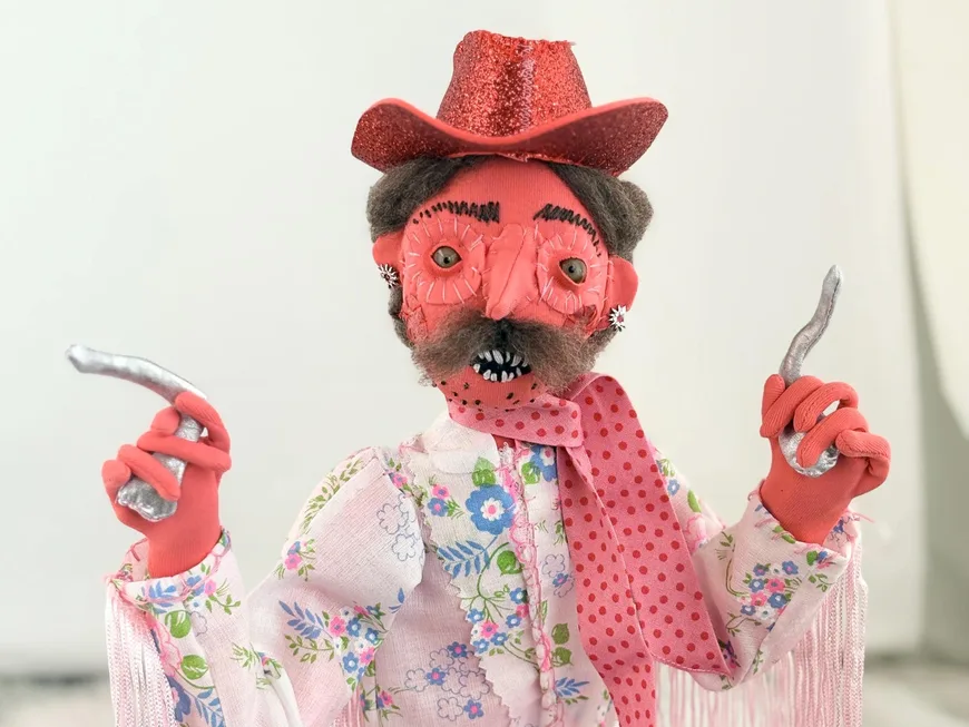 The Pink Cowboy, a red poseable art doll in a pink hat and fringed jacket